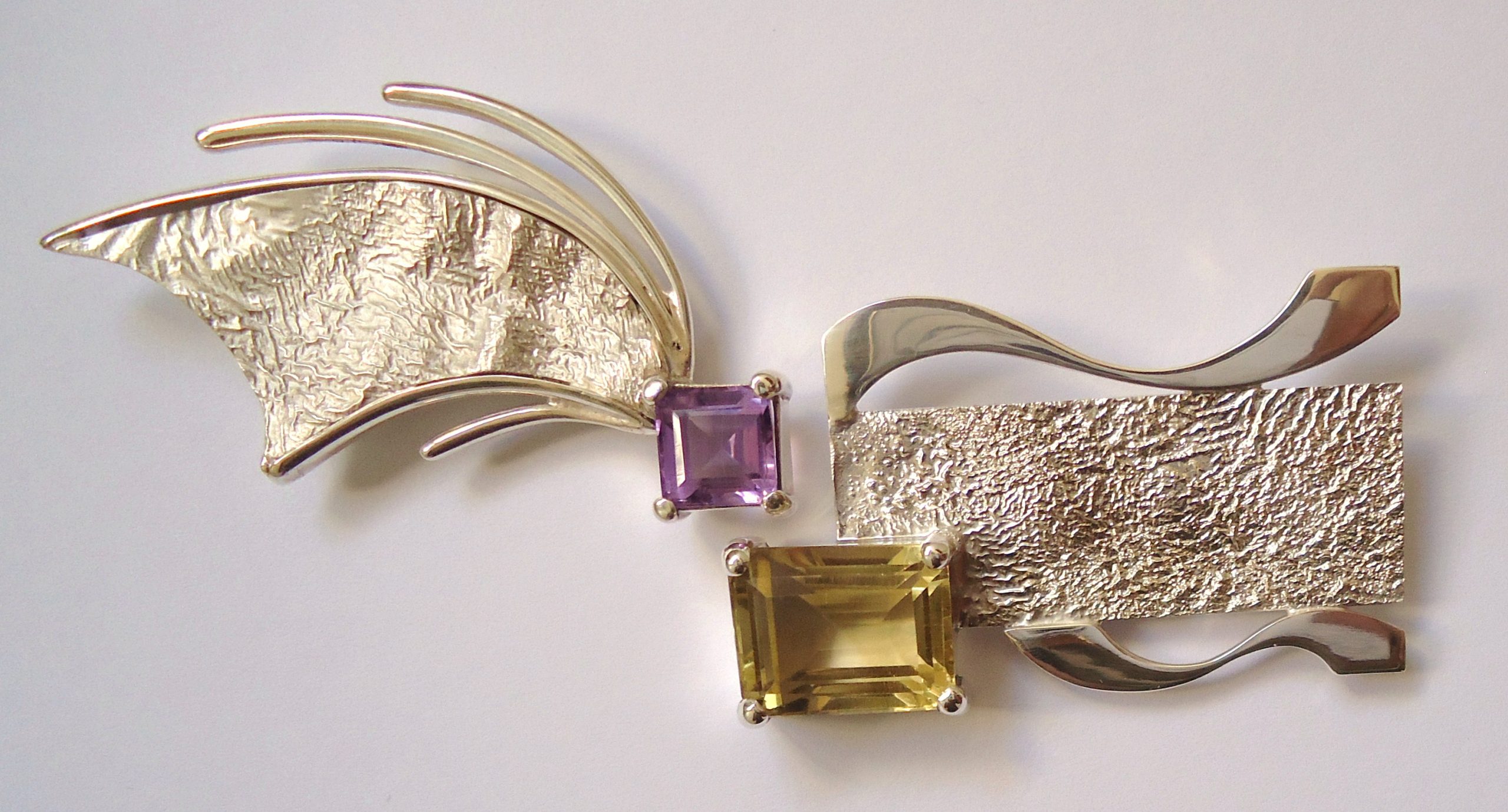 Deux broches en argent massif serties d'am&eacute;thyste et de citrine, pos&eacute;es c&ocirc;te &agrave; c&ocirc;te